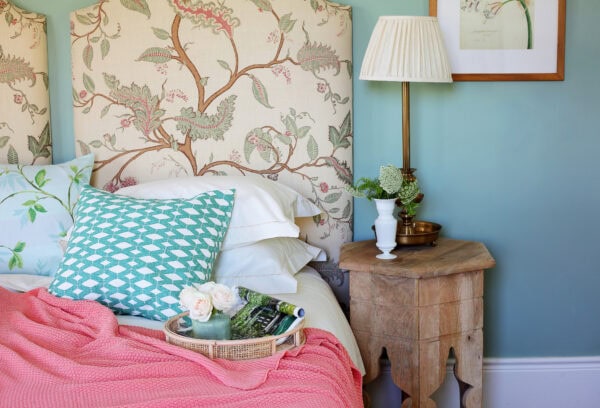 lifestyle image of blankets and pillows on a bed with a bedside table