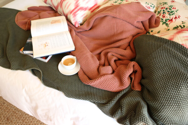 open book and coffee set atop blankets