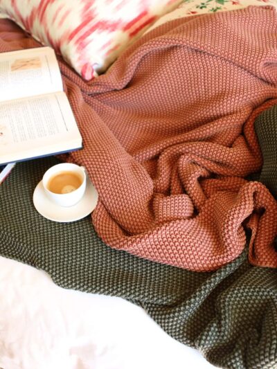 open book and coffee set atop blankets