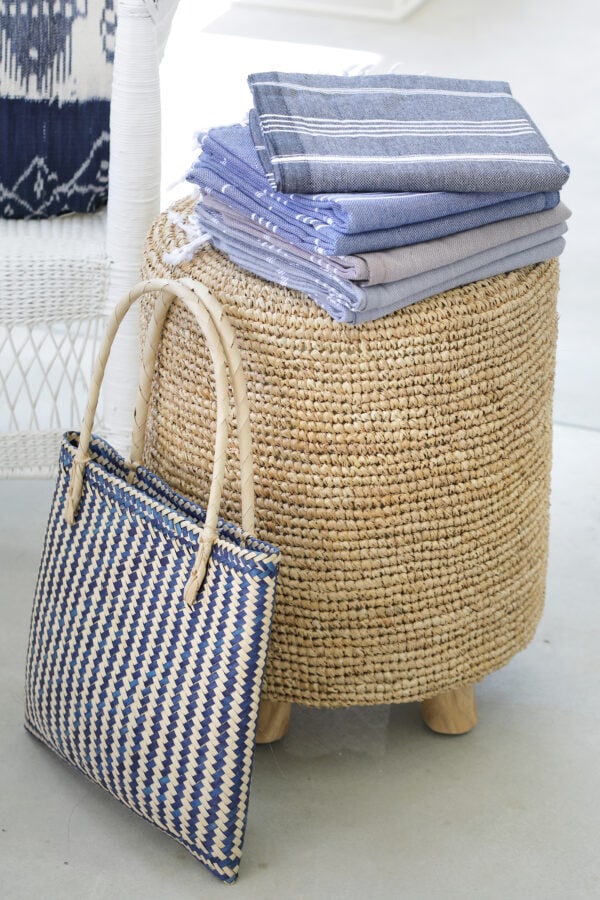 folded towels on a woven stool with woven carrier bag