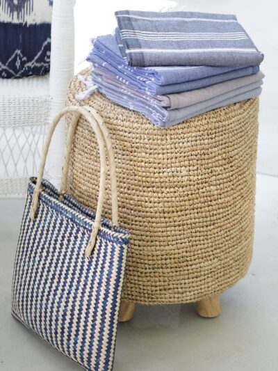 folded towels on a woven stool with woven carrier bag