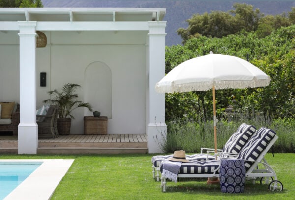 outdoor striped patio loungers with umbrella next to pool